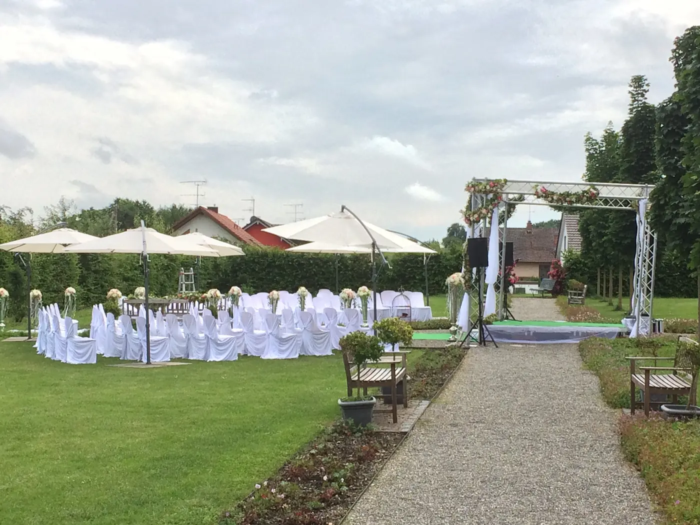 Freie Trauung im Garten mit weißen Stühlen, grünem Teppich und Traubogen