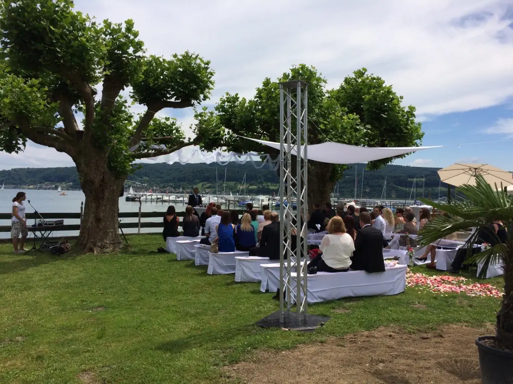 Trauung am See mit Baldachin und weißen Bänken